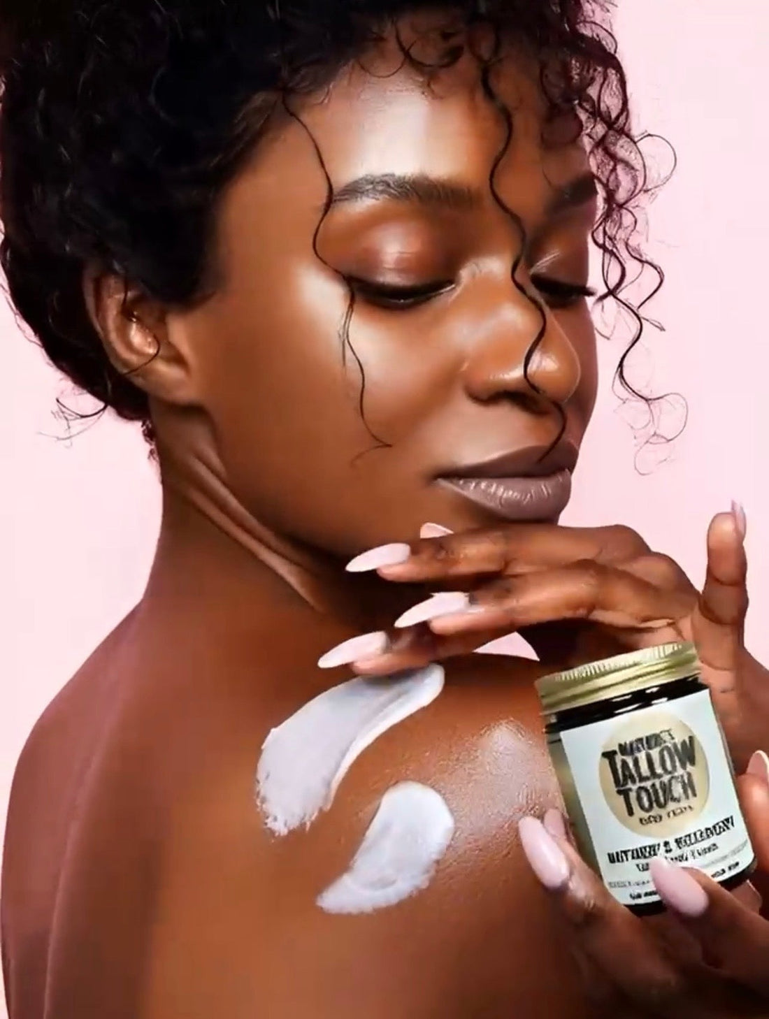Woman of color applying Mother’s Recovery Tallow Body Cream to shoulder; rich, satiny finish on skin.